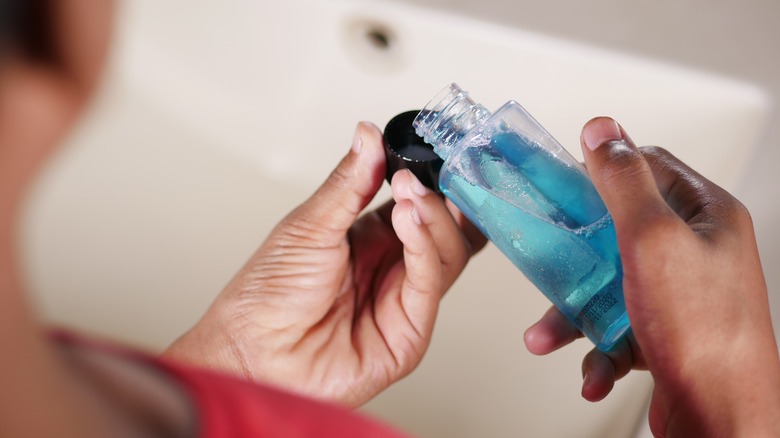 person pouring mouthwash in cup