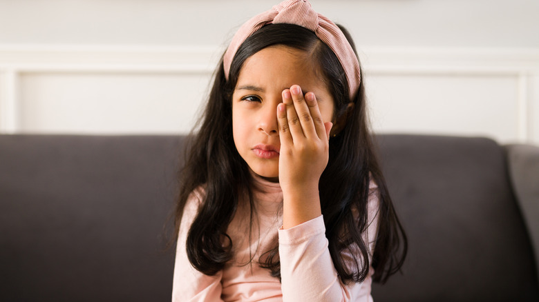 Young girl covering eye