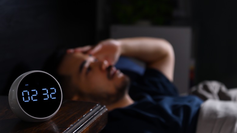 man with insomnia lies awake in bed