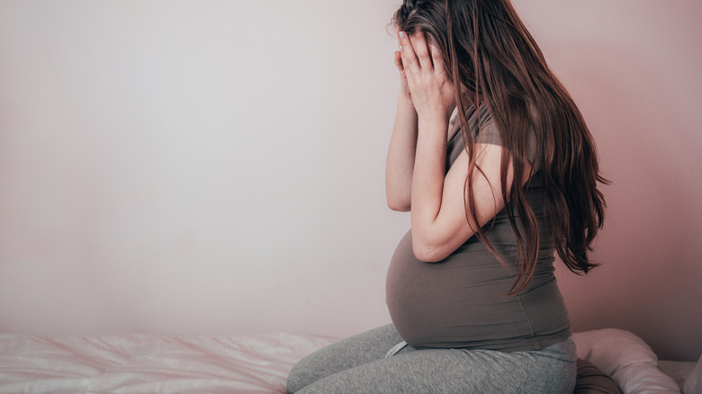 Pregnant woman holding head looking stressed