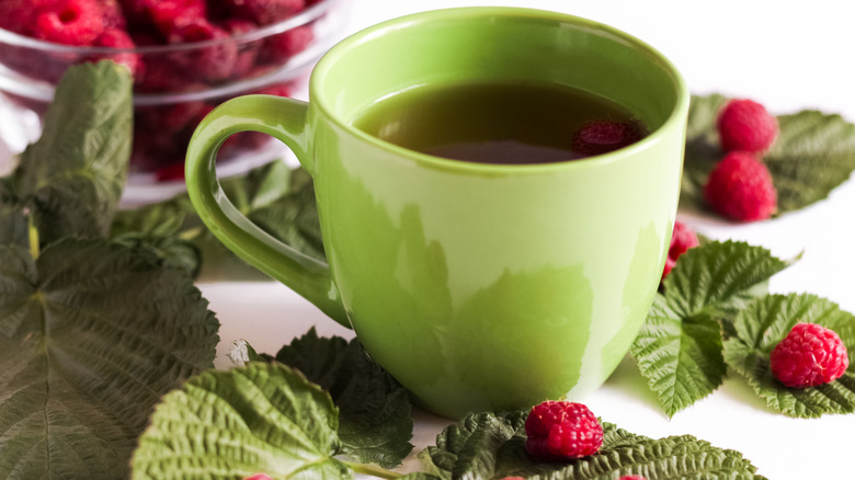 cup of tea surrounded by raspberries 