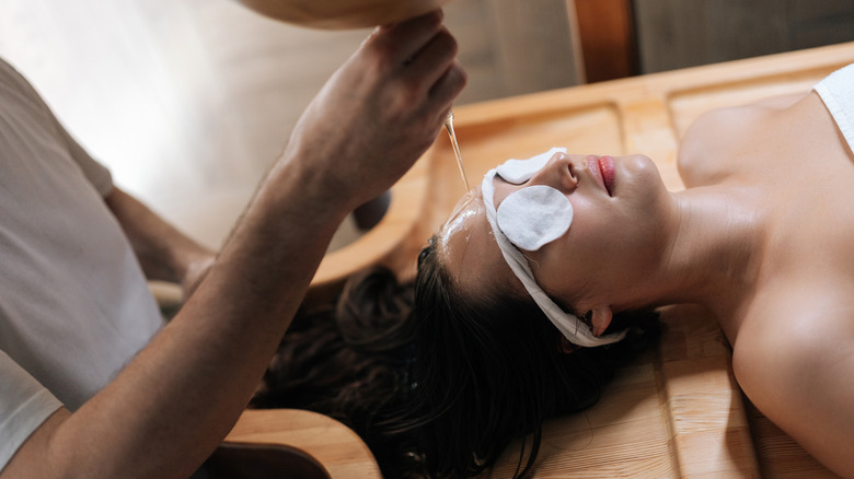 A woman having oil poured on her head