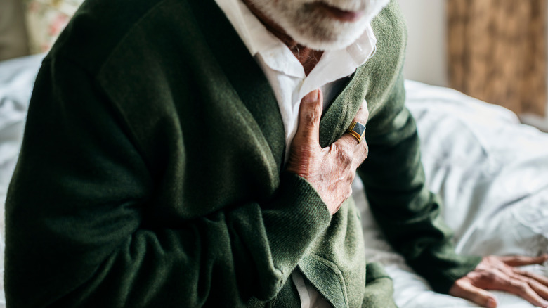 older man pressing his hand to his chest