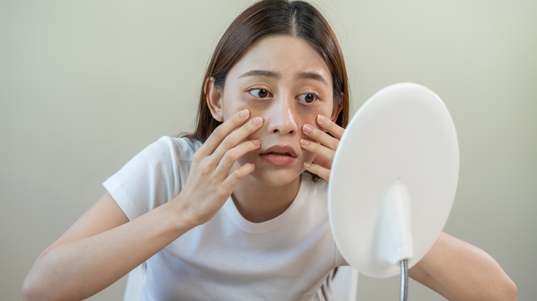 A woman looks at her puffy eyes