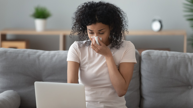 woman using computer and blowing nose