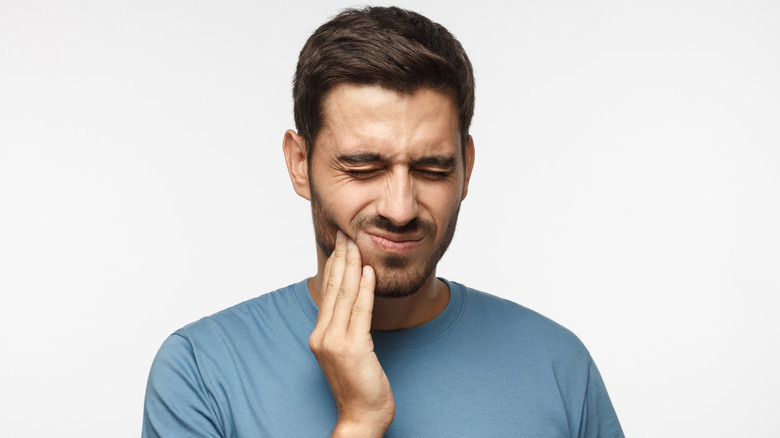 man holding hand on face wincing in pain