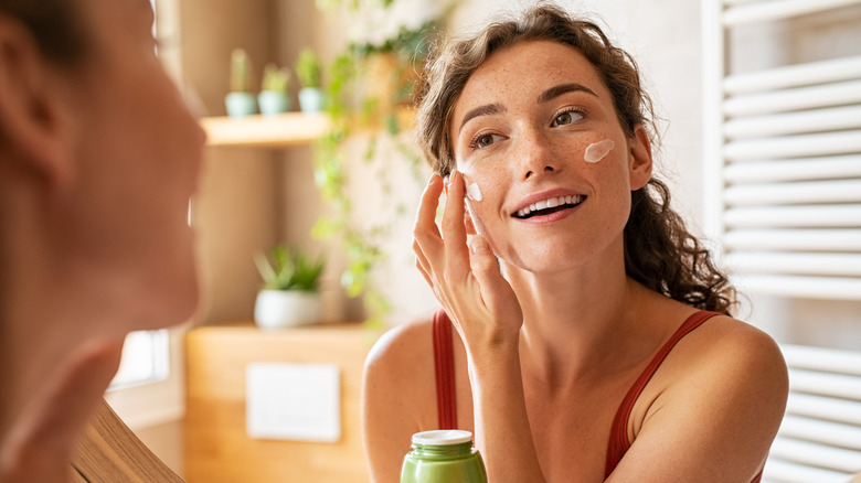 Woman putting on moisturizer 