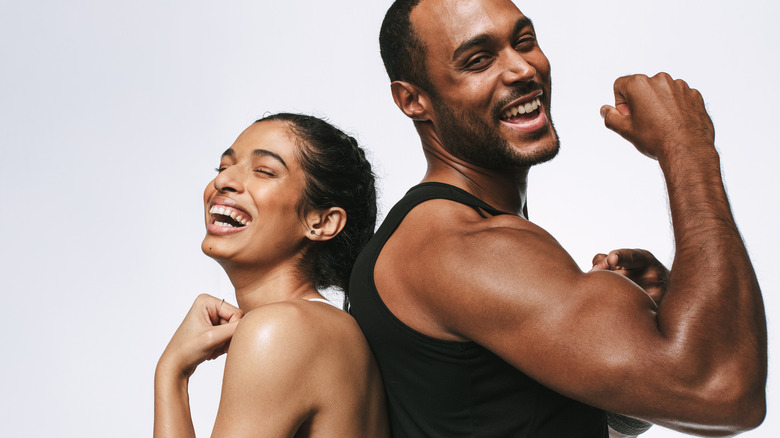 Couple standing back-to-back flexing 