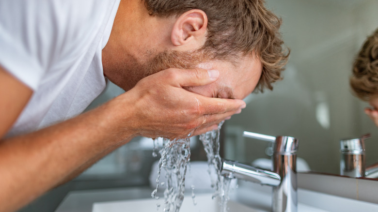 man splashing water on his face 