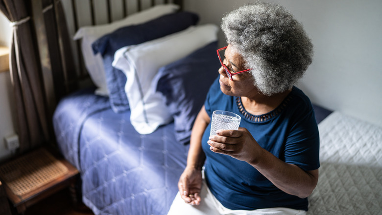 Woman holding pill and water glass