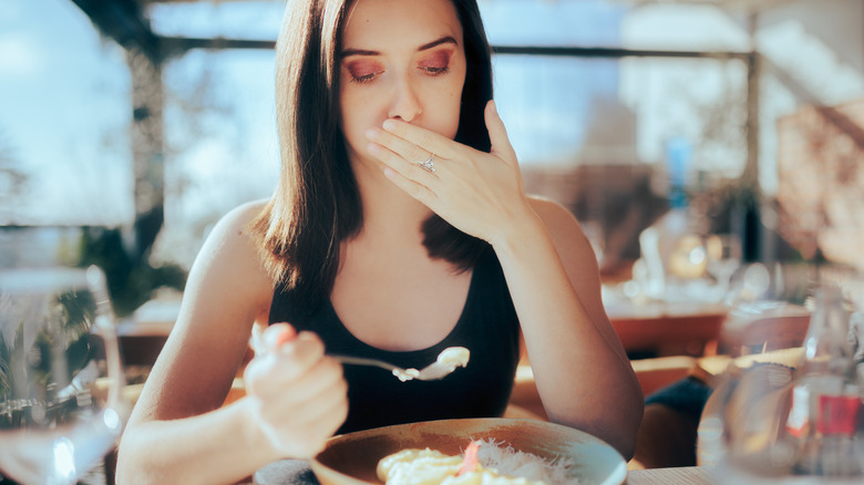 woman burping while eating a meal