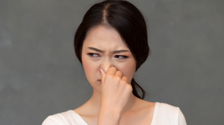 woman holding her hose with a disgusted look