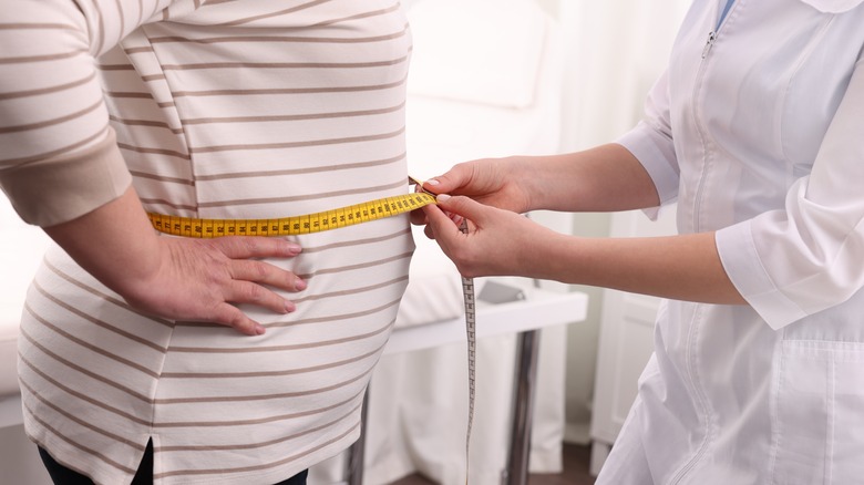 Woman at the doctor having waist measured