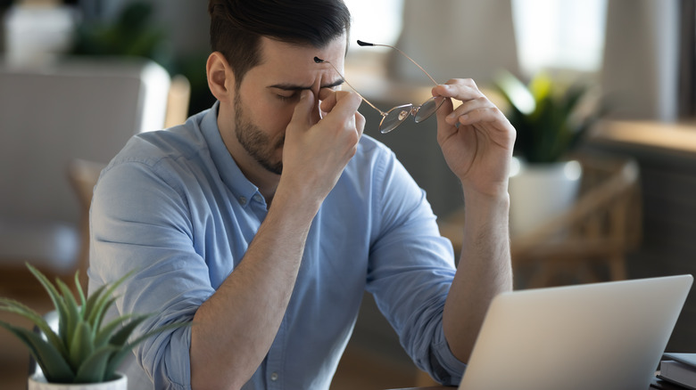 man at his desk rubbing his eyes from fatigue