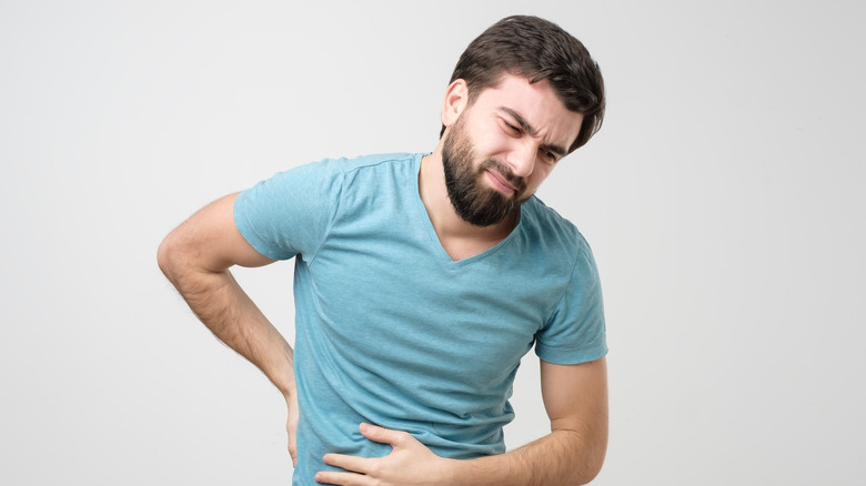 man holding stomach and back in pain