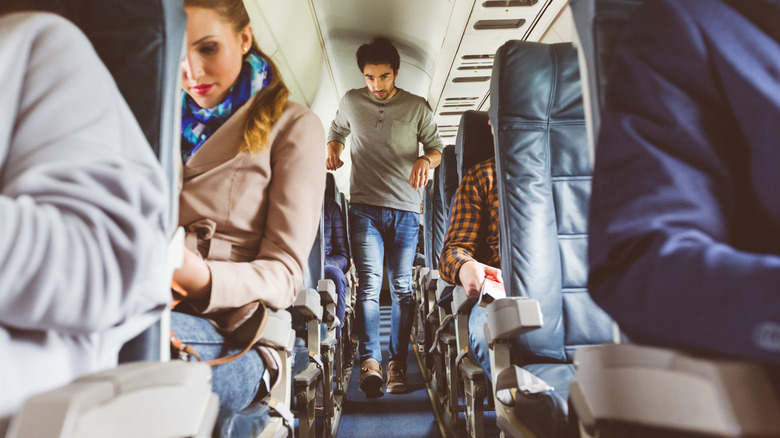 passenger walking down aisle of plane