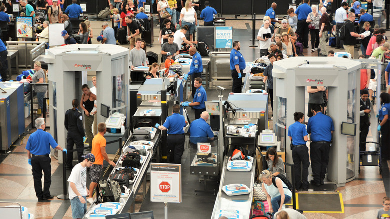 travelers preparing to go through TSA body scanners