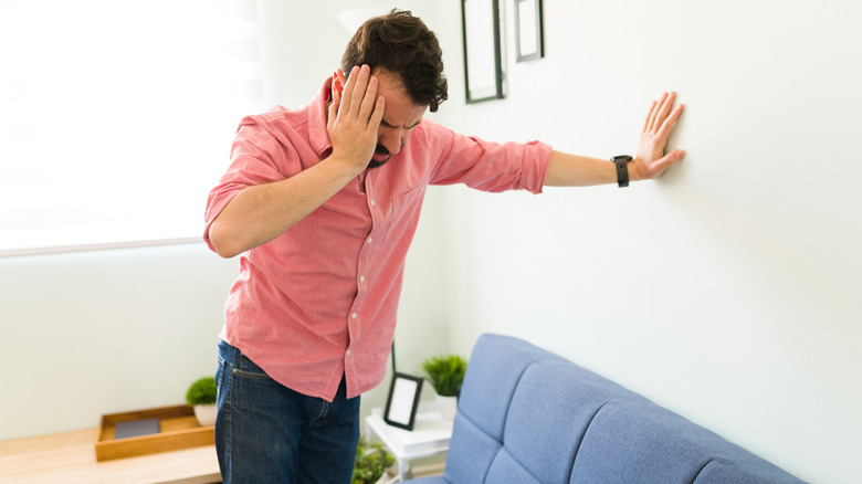 man with vertigo holding onto a wall