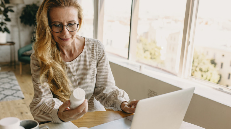 woman looking at vitamin bottle while at home