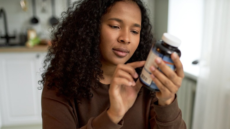 Woman reading label on supplements bottle
