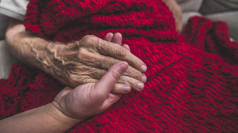 Old lady holding hands with younger person