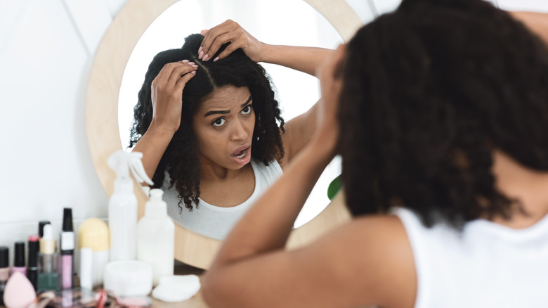 woman looks at hair loss in mirror 