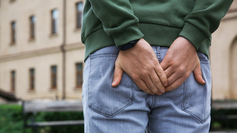 Man with hemorrhoid pain holding buttocks