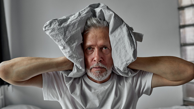 Older man covering his ears