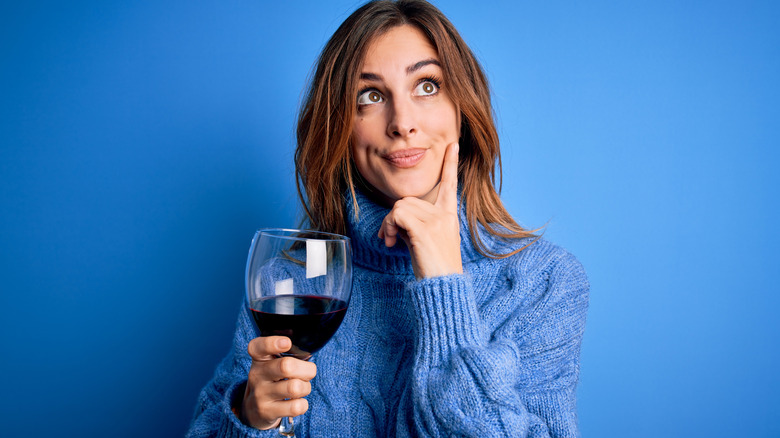 woman holding glass of wine and thinking