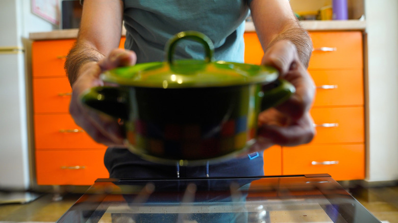 man putting baking dish with lid in oven