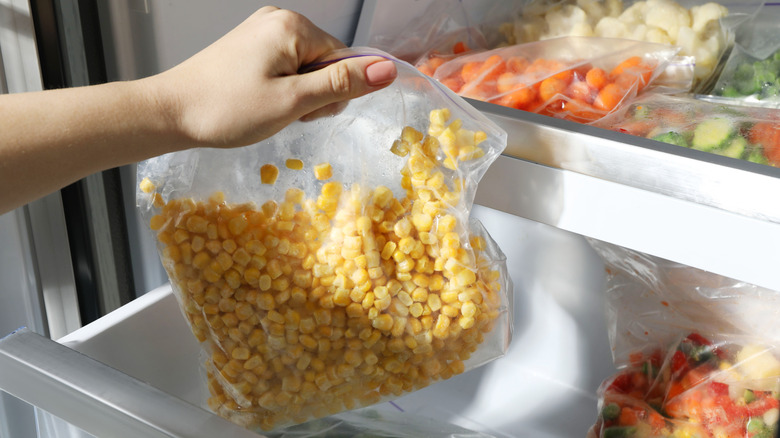 woman putting bag of corn out of freezer
