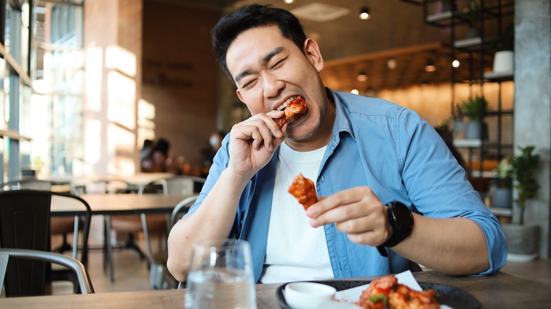 a man eating chicken wings