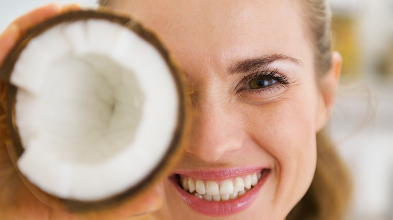 smiling woman holding an open coconut