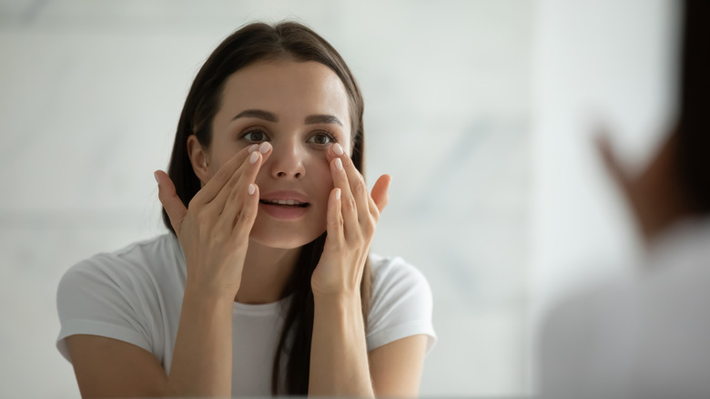 A woman checking her eyes in the mirror