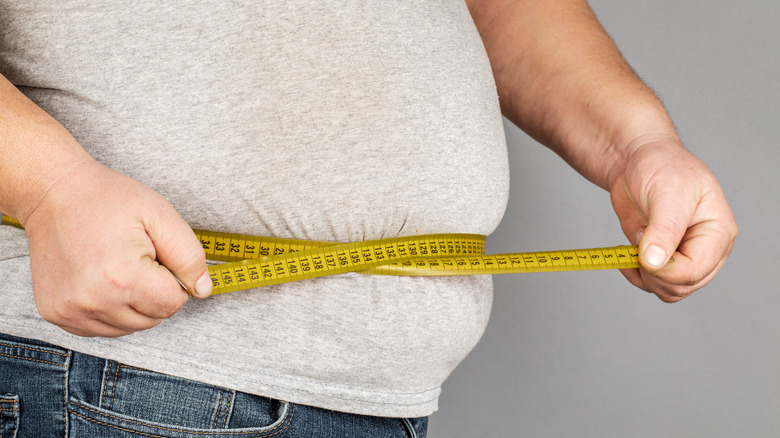Man cinching tape measure around waist