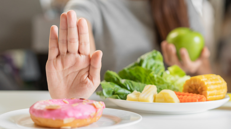 Woman holding up hand to donut