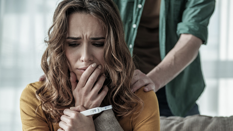 Nervous woman looking a pregnancy test with man