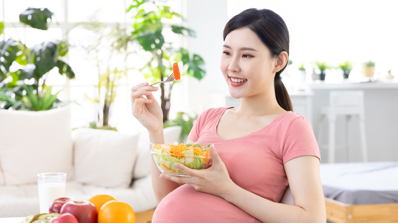 Pregnant Asian woman eating salad