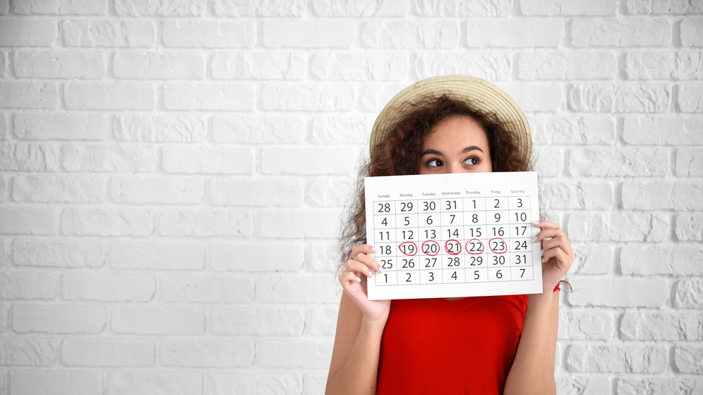 Woman holding calendar on white background