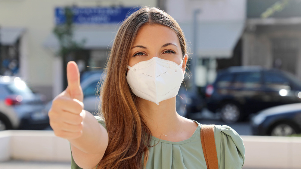 Young woman wearing a mask giving a thumbs up 