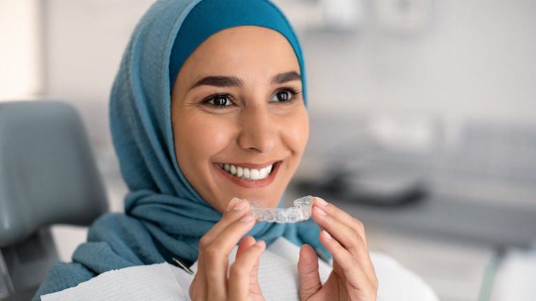 A woman holds a teeth aligner