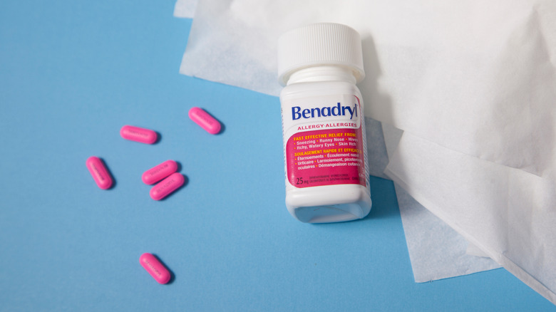A bottle of Benadryl next to a couple of pills