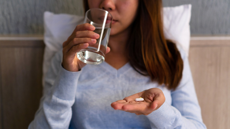 Woman in bed holding supplement