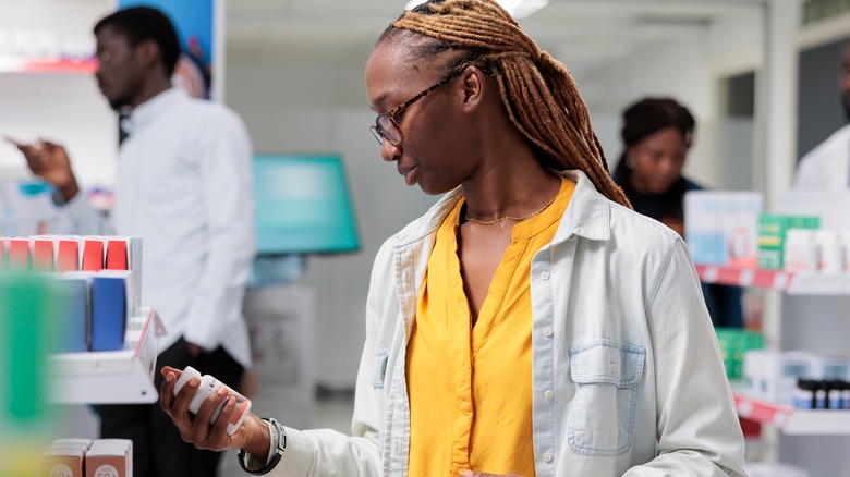woman looking at supplement label at a pharmacy