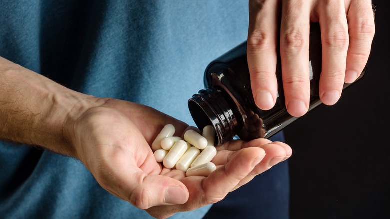 Hand pouring supplements into other hand