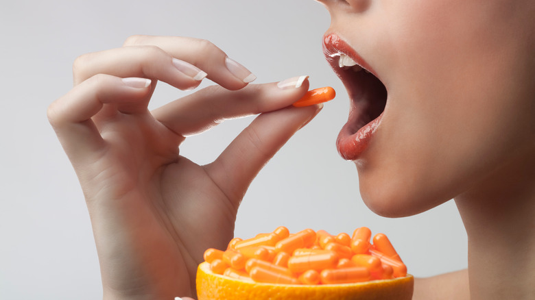 Woman taking orange vitamins