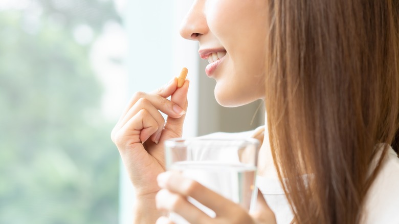 Woman taking medicine with glass of water