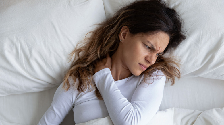 Woman waking up in bed with pain in neck