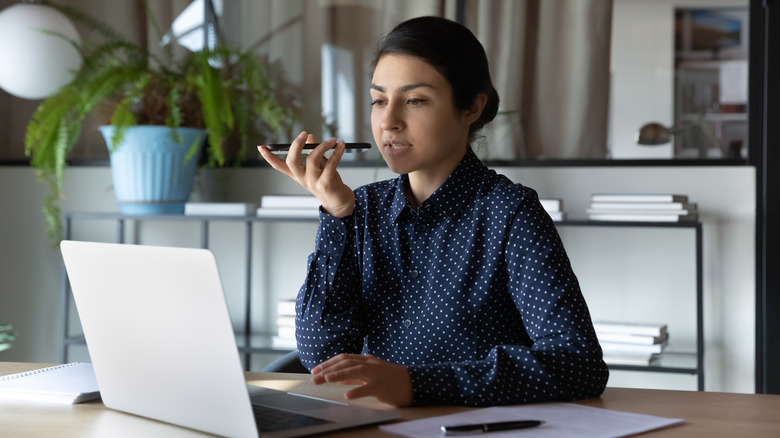 woman on computer speaking into phone