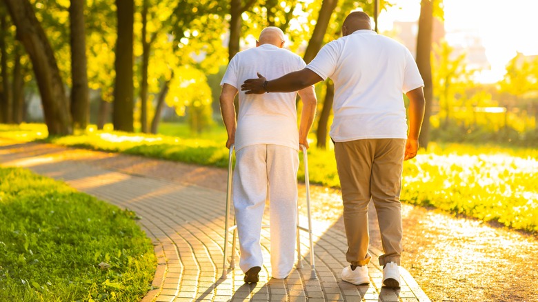 older man walking with caregiver